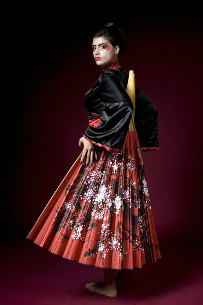 Sexy Geisha mit riesigem Fächer auf rotem Rücken — Stockfoto
