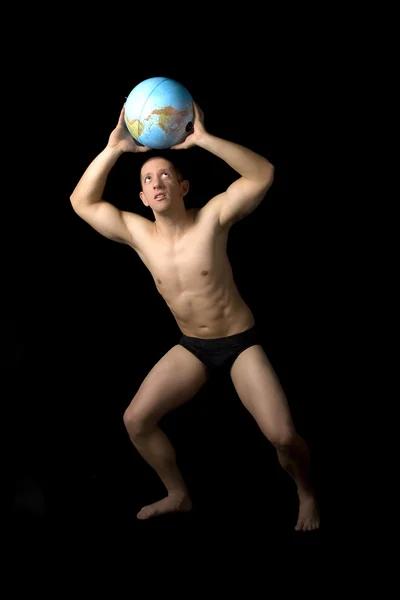 Muskulös ung man som håller en jordglob som ovan — Stockfoto