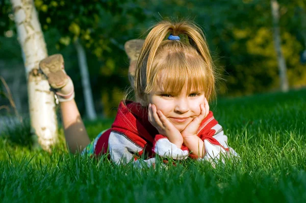 Маленькая красивая девочка на зеленой лужайке — стоковое фото