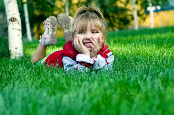 A menina bonita pequena em um gramado verde — Fotografia de Stock