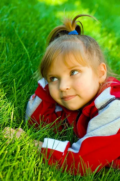 Das kleine schöne Mädchen auf dem grünen Rasen — Stockfoto