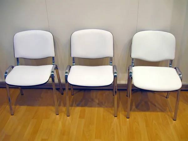 Несколько белых стульев на деревянном полу — стоковое фото