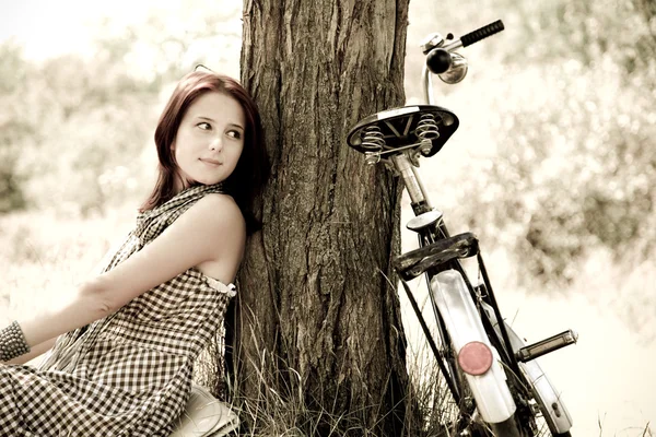 Piękna dziewczyna siedzi w pobliżu rower i drzewa w stanie spoczynku w lesie. zdjęcie w stylu retro — Zdjęcie stockowe