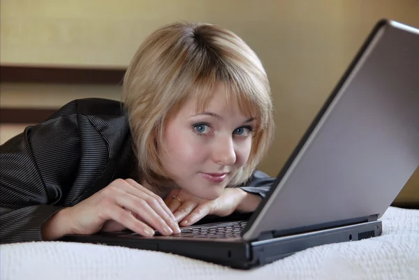 Το κορίτσι με το φορητό υπολογιστή σε ένα κρεβάτι — Φωτογραφία Αρχείου