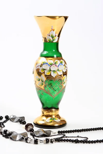 Хрустально-зеленая ваза и черные бусы — стоковое фото