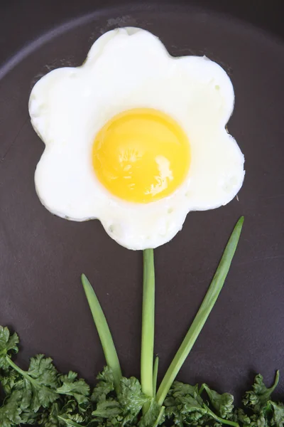 Flower shaped fried egg with greenery Stock Image