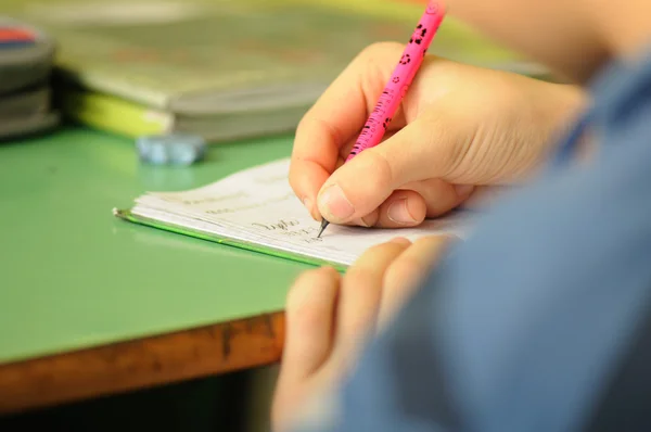 Criança em sala de aula com caneta na mão — Fotografia de Stock
