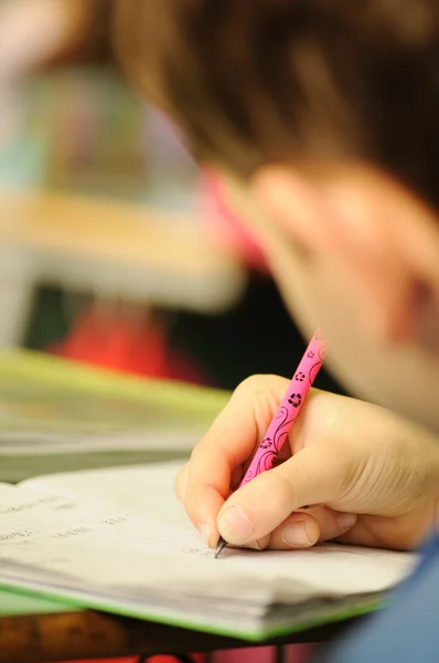 Criança em sala de aula com caneta na mão — Fotografia de Stock