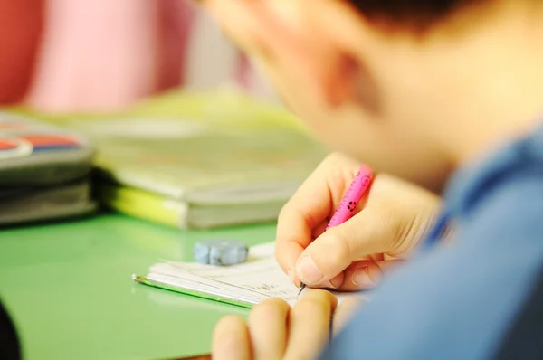 Kid i klassrummet med pennan i hand — Stockfoto