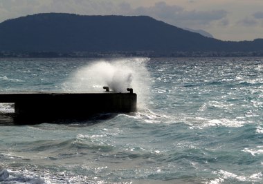 Wave breaking against stone mooring clipart