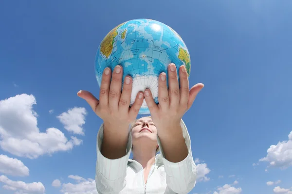 Vrouw met een globe onder de blauwe hemel — Stockfoto