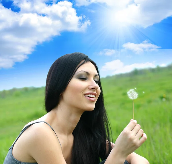 Beautiful woman blowing dandelion — Stock Photo, Image