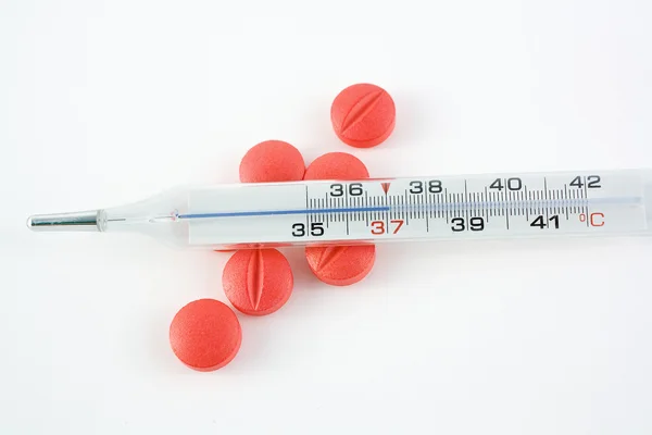 Θερμόμετρο και χάπια, πάνω από το λευκό backgro — Φωτογραφία Αρχείου