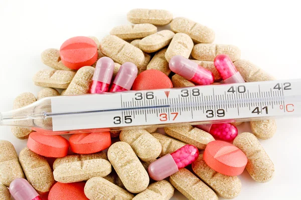 Termômetro e pílulas sobre backgro branco — Fotografia de Stock
