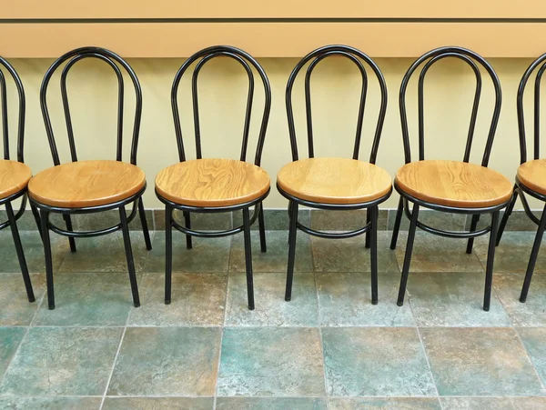 Chaises vides alignées contre un mur — Photo