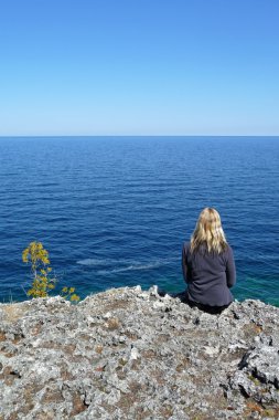 Blond woman relaxing cliff edge clipart