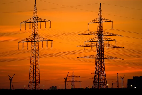 Linhas de energia e turbinas eólicas ao pôr do sol — Fotografia de Stock