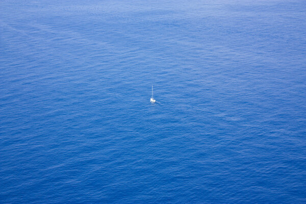 Single boat sailing in a vast ocean