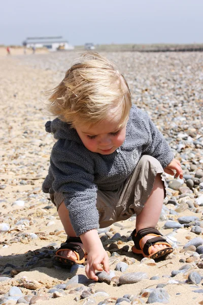 Kind op strand met steentjes — Stockfoto