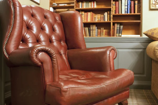 Кресло в старом стиле перед книжной полкой — стоковое фото