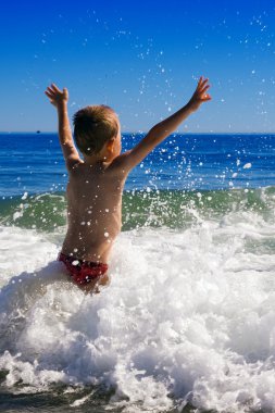 Young child playing in the waves clipart