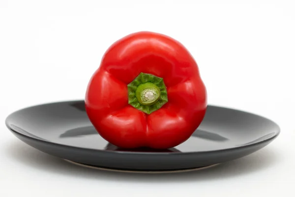 Red pepper on a black plate — Stock Photo, Image