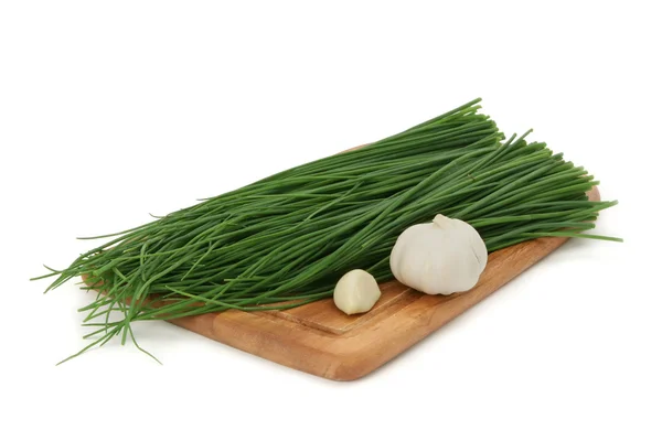 Zelené cibule a česnek na desce — Stock fotografie