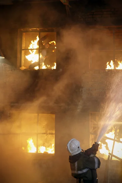 Pompiere che combatte un incendio. Uomo ustionato — Foto Stock