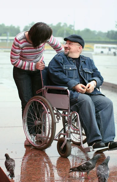 Uomo su una sedia a rotelle che parla con una donna — Foto Stock