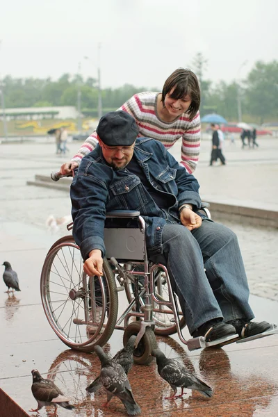 Hombre en silla de ruedas alimentando pájaros — Foto de Stock