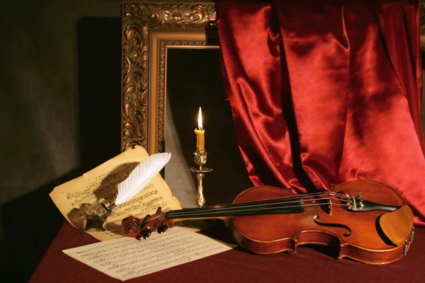 Скрипка, свеча и перо — стоковое фото