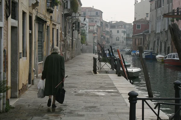 Старуха, идущая по каналу в Вени — стоковое фото