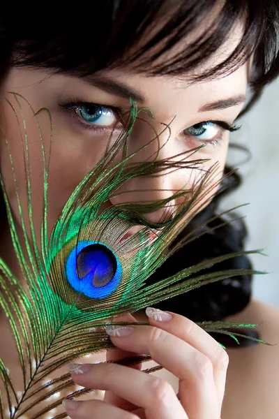 Girl and a feather of a peacock — Stockfoto