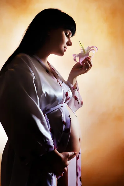 Piękna kobieta w ciąży z lily. — Zdjęcie stockowe
