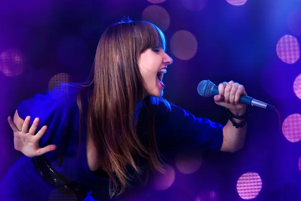 Młoda kobieta śpiewająca do mikrofonu — Zdjęcie stockowe