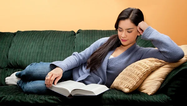 Νεαρή γυναίκα ξαπλωμένη και την ανάγνωση του βιβλίου Εικόνα Αρχείου