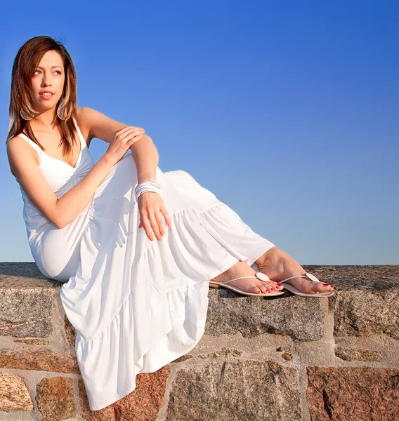 Senhora sentada no topo de uma parede de pedra — Fotografia de Stock