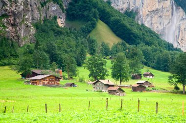 Houses close to a Steep Rocky Mountain clipart