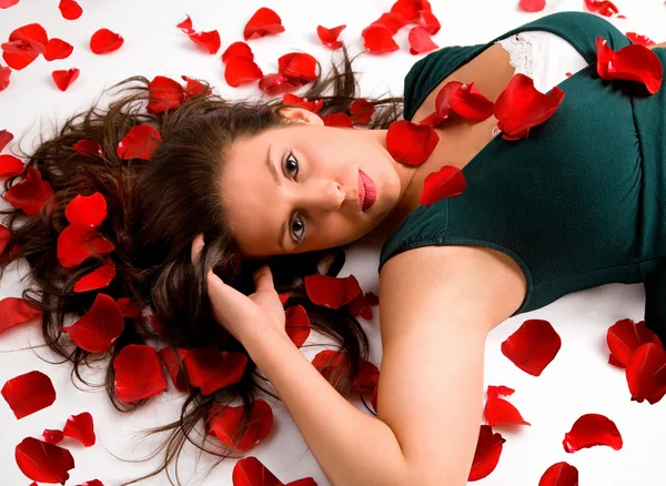 Junge Frau liegt in Rosenblättern — Stockfoto