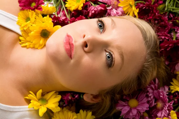 Mulher jovem que põe em flores — Fotografia de Stock