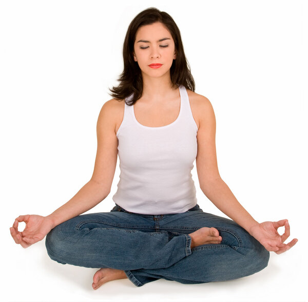A beautiful young woman is meditating while assuming a yoga position.