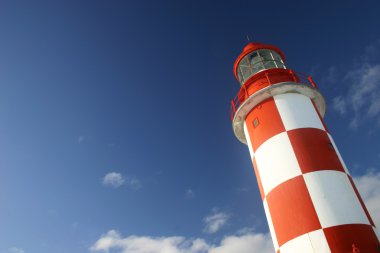 Lighthouse Under a Deep Blue Sky clipart