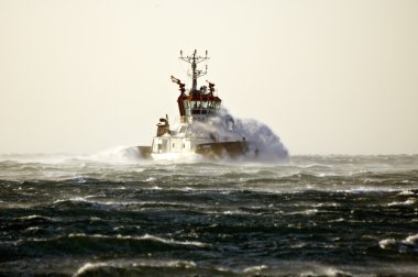 Tuboat ploughing a rough sea clipart