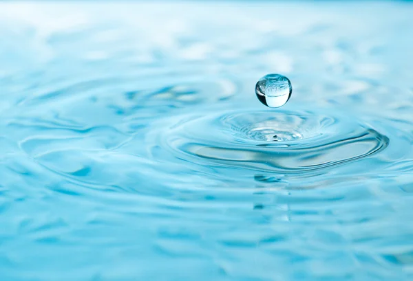 Gota suspensa acima da piscina de aqua transparente — Fotografia de Stock
