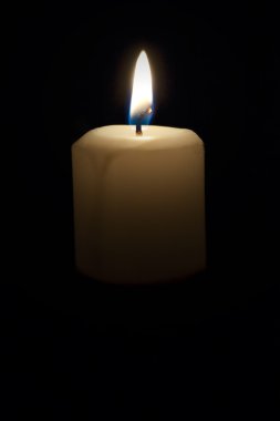 Lighted candle against a dark background clipart