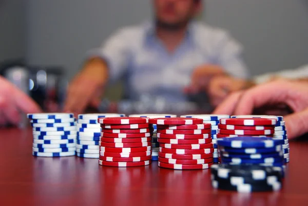 Poker žetony s hráči v pozadí — Stock fotografie