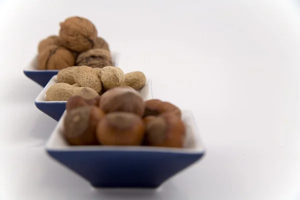Valnötter, hasselnötter och jordnötter i tre skålar — Stockfoto