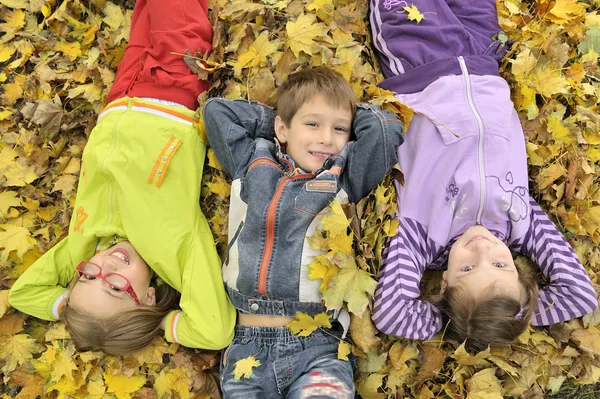 Crianças deitadas nas folhas — Fotografia de Stock