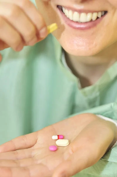 Mulher segura pílulas em uma mão — Fotografia de Stock