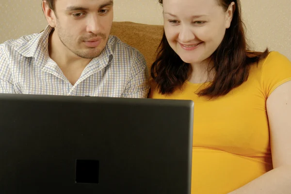 妊娠中の女性と彼女の夫 lapt で — ストック写真